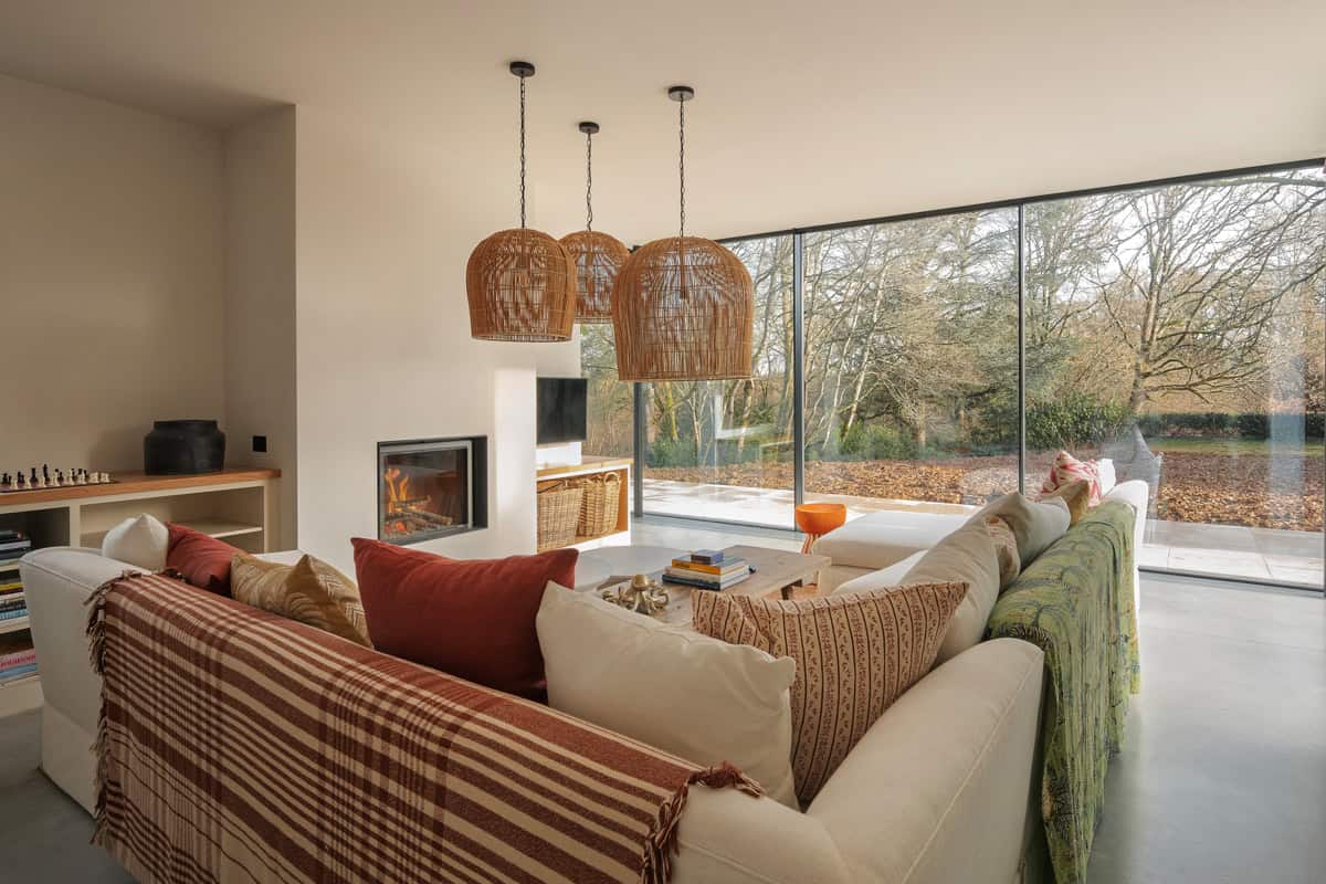Hazelbridge Cottage living room with sofa, rattan pendants, fireplace, and full-width garden glazing